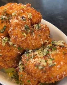 some fried food on a white plate with parmesan sprinkles and seasoning