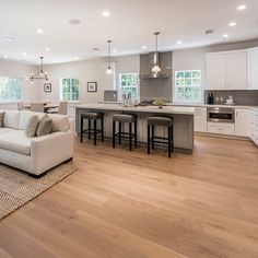 a living room filled with furniture next to a kitchen and breakfast nook area on top of a hard wood floor