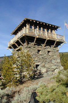 an old stone building on top of a hill with a flag flying in the wind