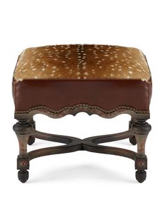 the foot stool is made from wood and has a brown leather cushion with white spots on it