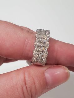 a person's hand holding a diamond ring in their left hand with the middle finger