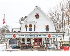 the town landing market is decorated with wreaths and holiday decorations on display in front of a white building