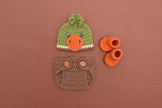 three crocheted hats and two baby booties on a brown surface with pink background