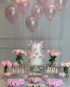 a table topped with a white cake and lots of pink flowers