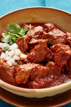 a brown bowl filled with meat and onions