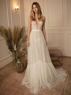 a woman in a white wedding dress standing next to a plant