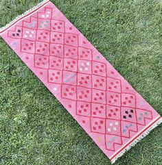 a red and pink rug laying on top of green grass