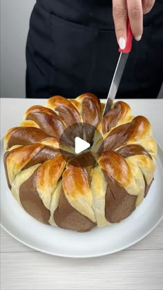 a person cutting into a bundt cake on a white plate with a knife in it