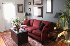 a living room with red couches and pictures on the wall above them, along with a coffee table