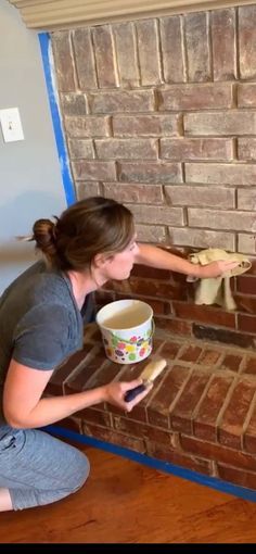 a woman is painting a brick wall with paint