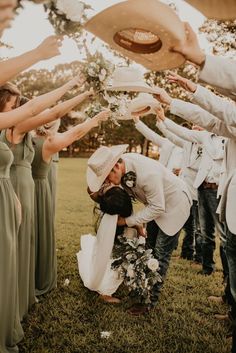 a group of people standing around each other in the grass with hats on their heads