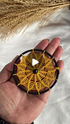 a hand holding a yellow and black beaded brooch with an arrow on it