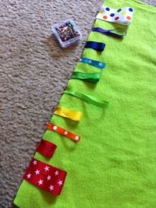 a green christmas tree made out of strips of fabric and tape on the floor next to a toy