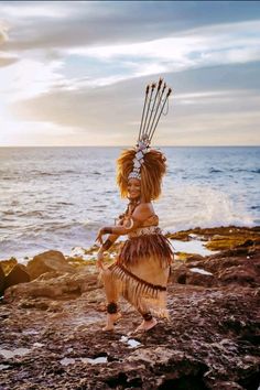 a native american woman dancing on the rocks by the ocean