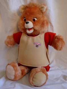 a brown teddy bear with an apron on it's chest and tongue sticking out