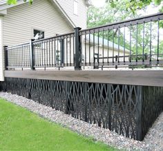 a black iron fence on the side of a house with green grass and trees in the background