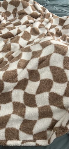 a brown and white blanket sitting on top of a bed