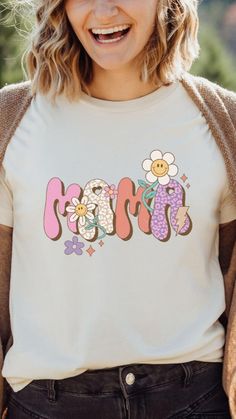 a woman wearing a t - shirt with the word mom printed on it and smiling