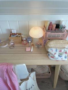 a wooden desk topped with lots of personal care items next to a lamp and bag