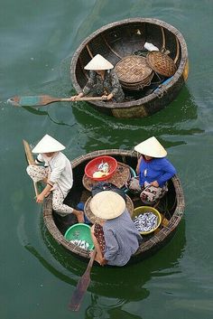 three people in small boats with hats on their heads and paddles out to sea