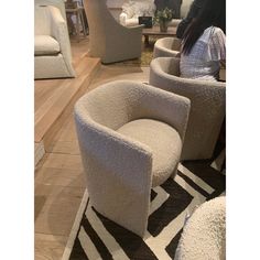 a woman sitting in a room with chairs and rugs