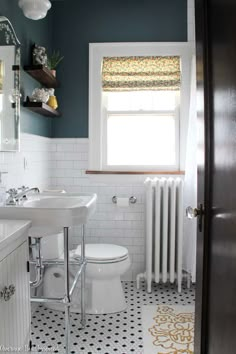 a white toilet sitting next to a sink in a bathroom under a window with a radiator