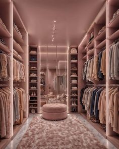 a walk - in closet with lots of clothes on hangers and a round ottoman