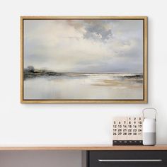 a painting hanging on the wall next to a desk with a calendar and pen in front of it