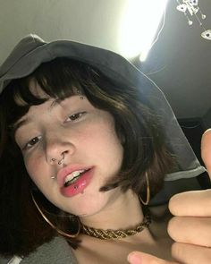 a young woman with piercings on her nose holding a cell phone up to the camera