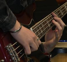 a person playing an electric guitar with their hands on the neck and fingers holding it