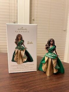 a barbie doll in a green and gold dress next to a box on a table