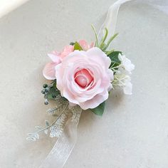 a pink rose and white flowers are tied to the side of a bridal bouquet