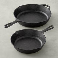 two black frying pans sitting side by side on a gray countertop, one is empty and the other has no lid