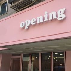 a pink building with the words opening on it's front door and windows that are open