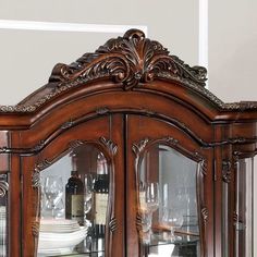 a wooden china cabinet with glass doors and wine glasses on it's side shelves