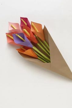 an origami flower bouquet is displayed on a white surface with paper folded around it