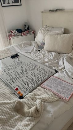 an unmade bed with sheets and pillows on it, next to a large sheet of paper