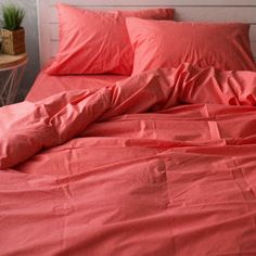 an unmade bed with red sheets and pillows