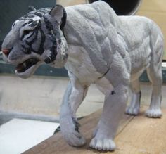 a paper mache of a white tiger on a wooden table with its mouth open