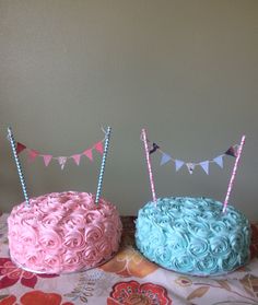 two cakes sitting on top of a table covered in pink and blue frosting