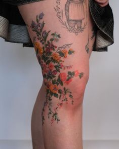 a woman's legs with tattoos on them and flowers all over the leg area