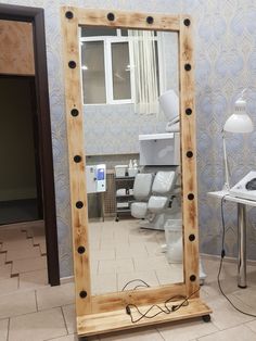 a mirror sitting on the floor in front of a table with a lamp and chair