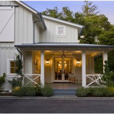 a white house with porches and lights on the front door is lit up at night