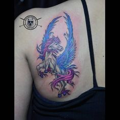 a woman with a tattoo on her shoulder has a pink and blue winged horse in the shape of a heart