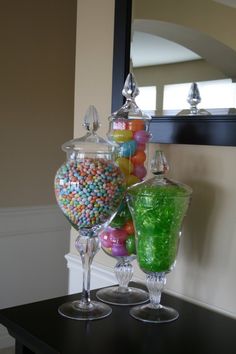 there are two glass vases with candy in them on the table next to each other