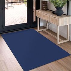 a blue area rug is in front of a wooden table with a potted plant on it