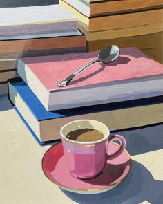 a cup of coffee sitting on top of a pink saucer next to stacks of books