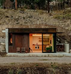 a small house on the side of a hill with sliding glass doors that open up