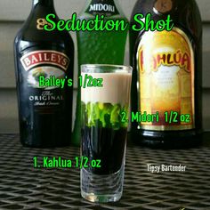 there is a shot glass with green liquid in it and two bottles next to it