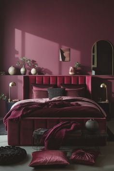 a bedroom with pink walls and purple bedding, black furniture and mirror on the wall